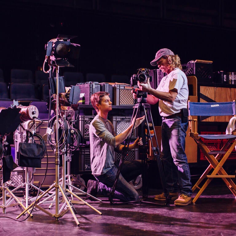 two people on stage setting up lighting