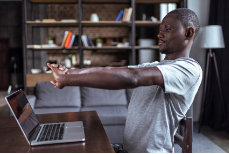 Person stretching arms in front of a laptop